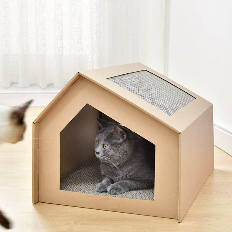 Grijze kat ligt in het kartonnen kattenhuisje